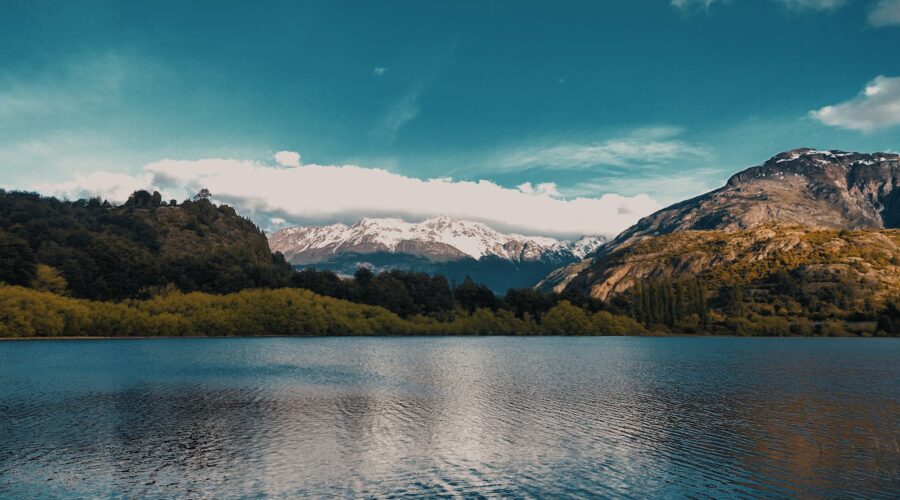 Calm lake with snow-capped mountains and lush greenery in Futaleufú, Chile.