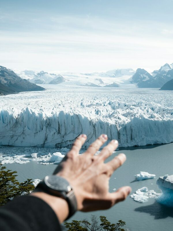 A hand reaching out towards a glacier