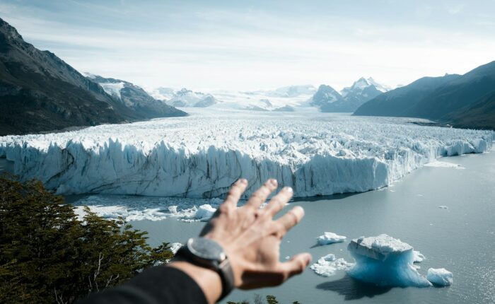 A hand reaching out towards a glacier
