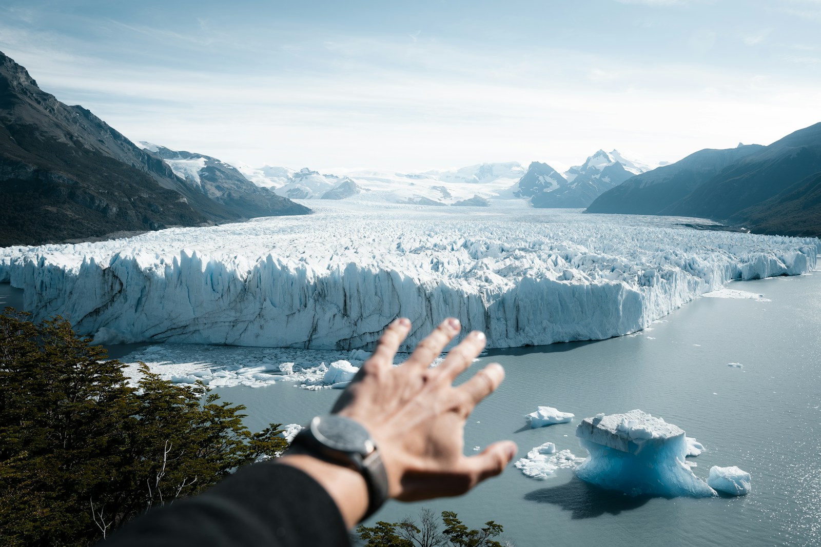 A hand reaching out towards a glacier