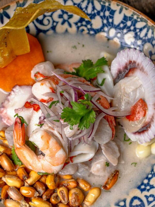 Close-up of vibrant ceviche with seafood, corn, and garnishes.