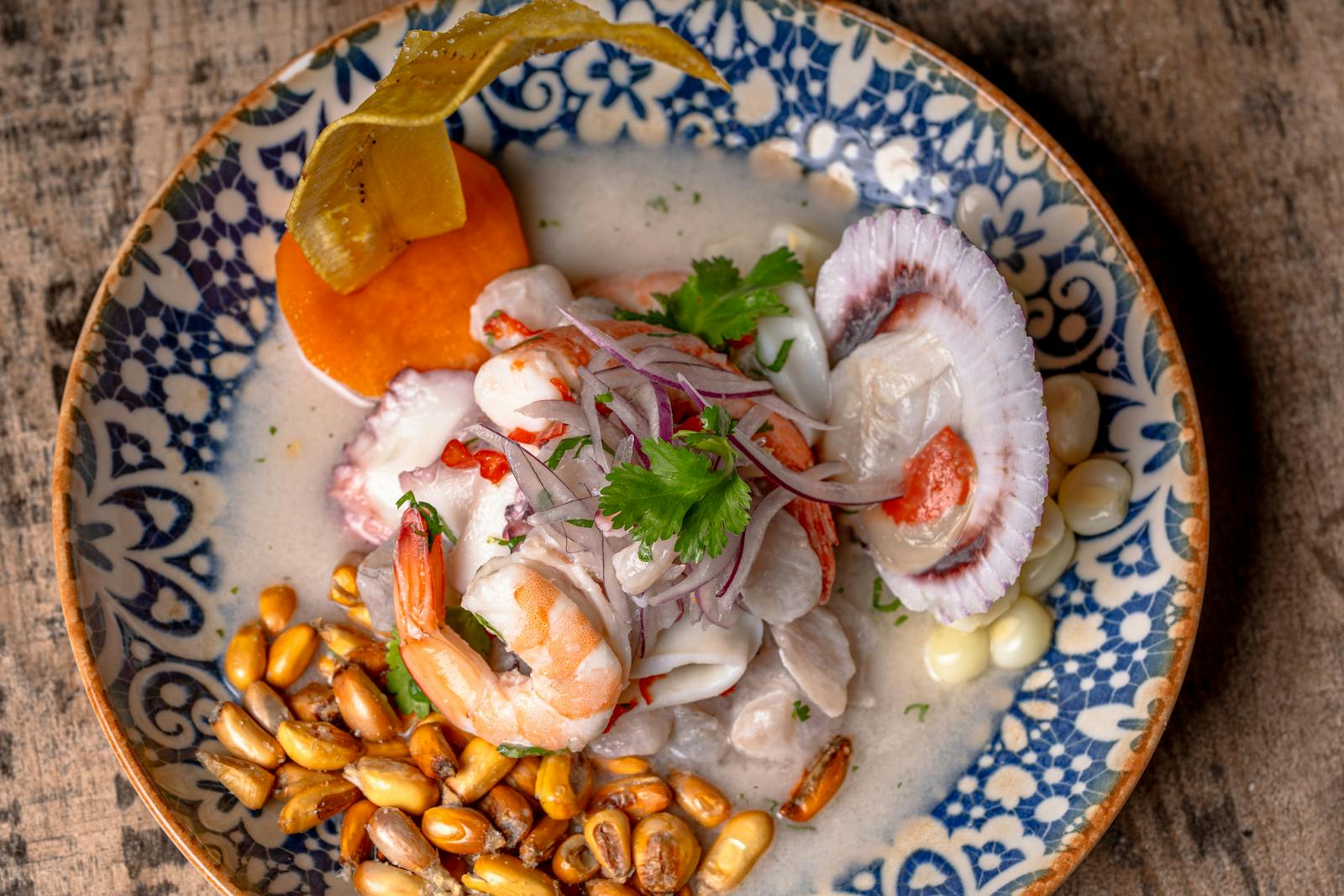 Close-up of vibrant ceviche with seafood, corn, and garnishes.
