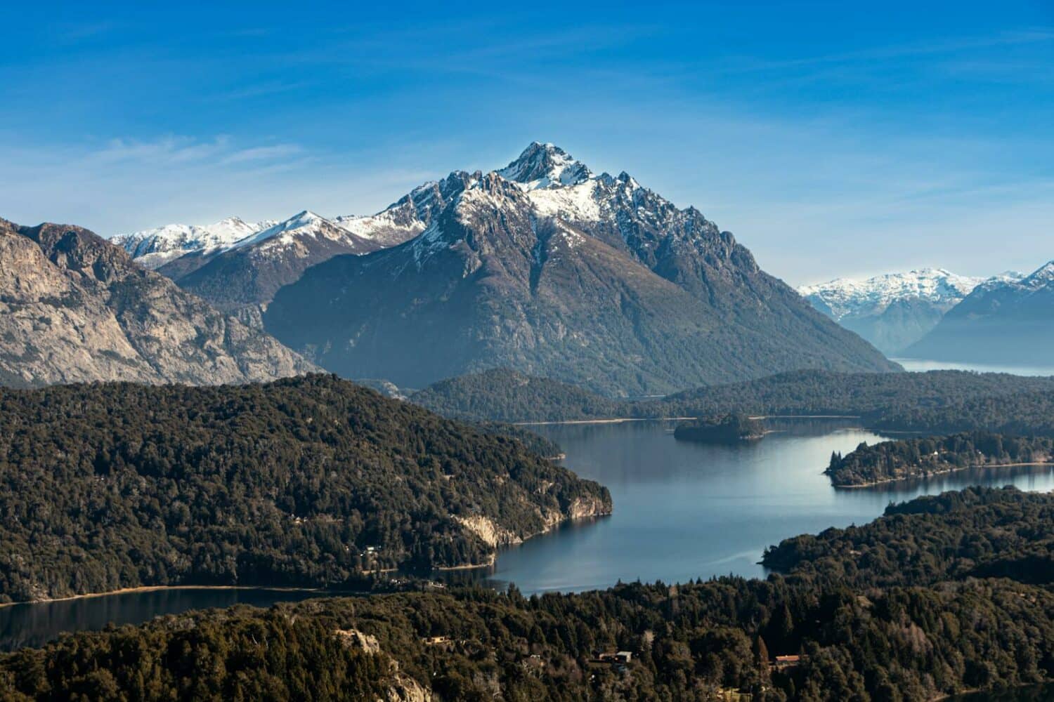 A breathtaking view of the Andes Mountains and Lake Nahuel Huapi, Argentina, under a clear blue sky.